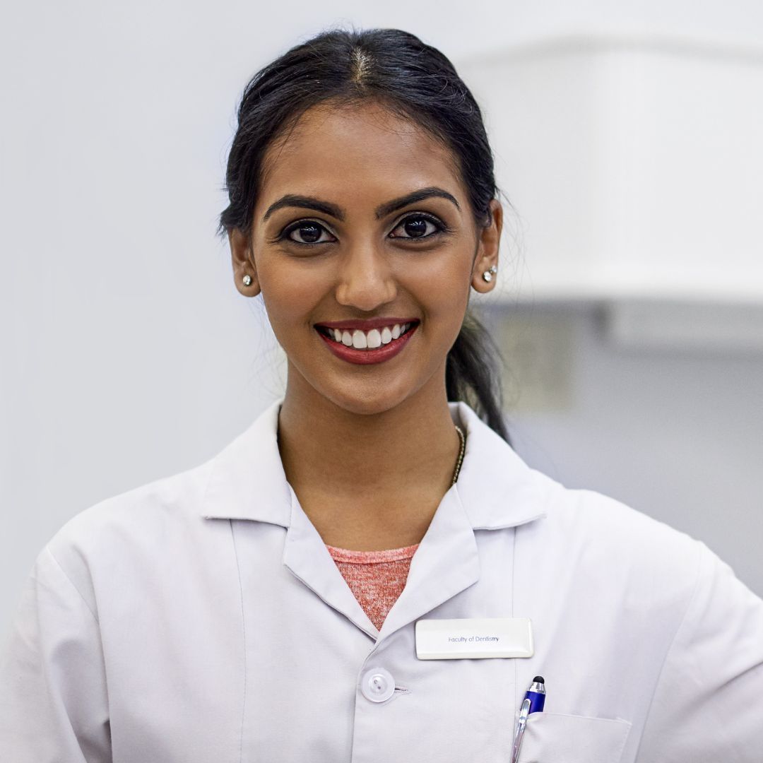 A woman in a lab coat is smiling for the camera