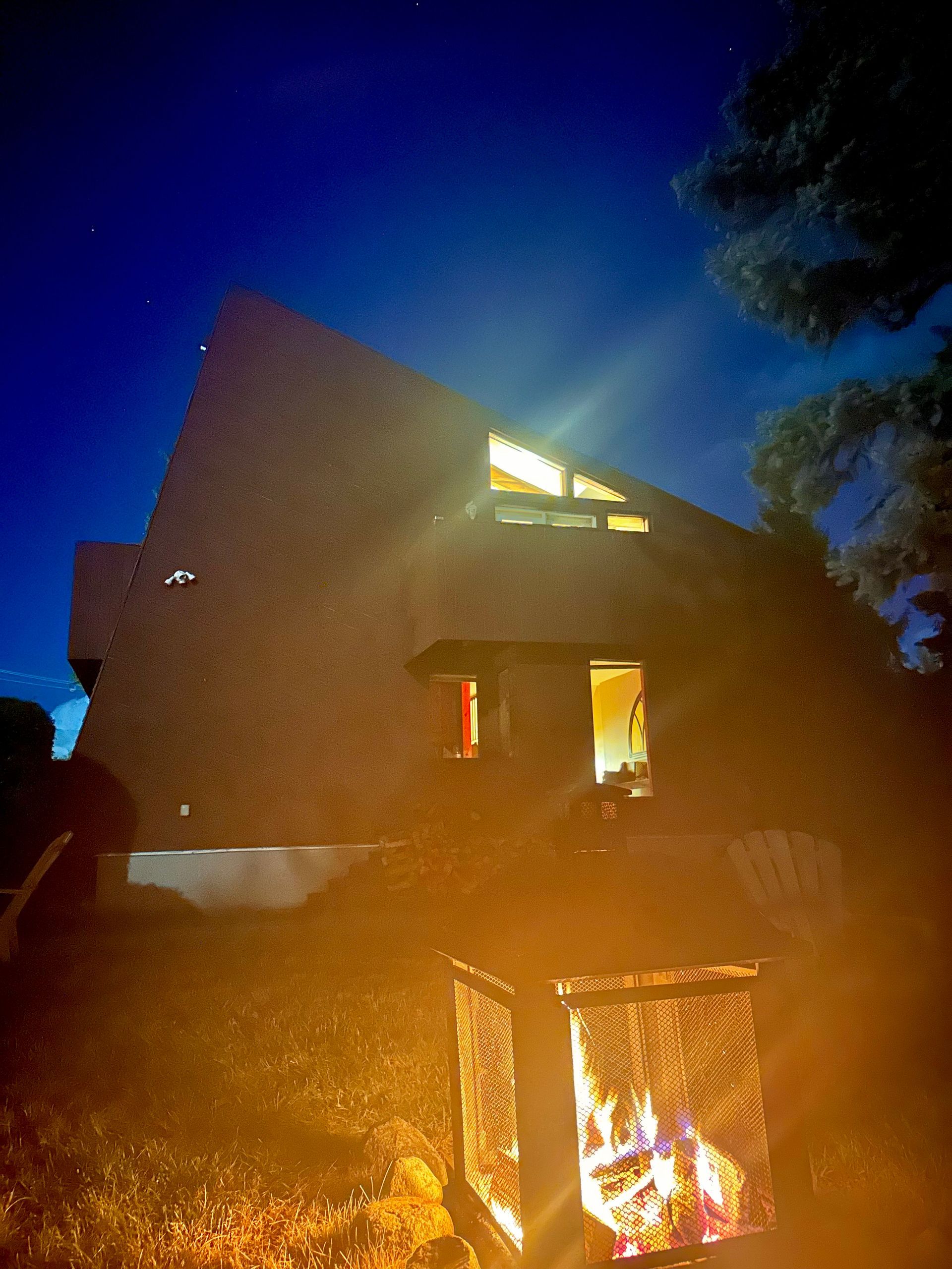 A house with a fire pit in front of it at night.