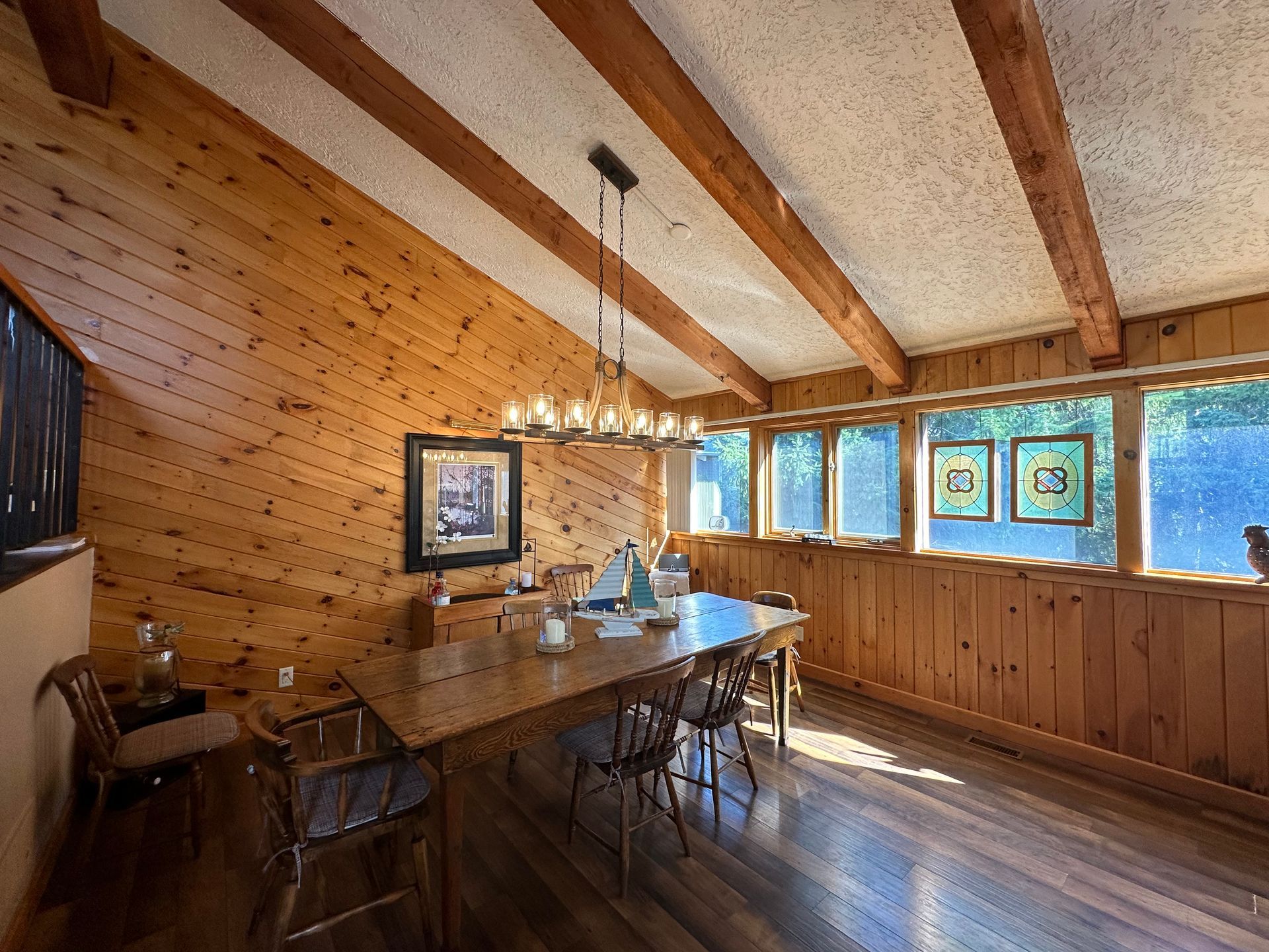A dining room with a wooden table and chairs and a chandelier.