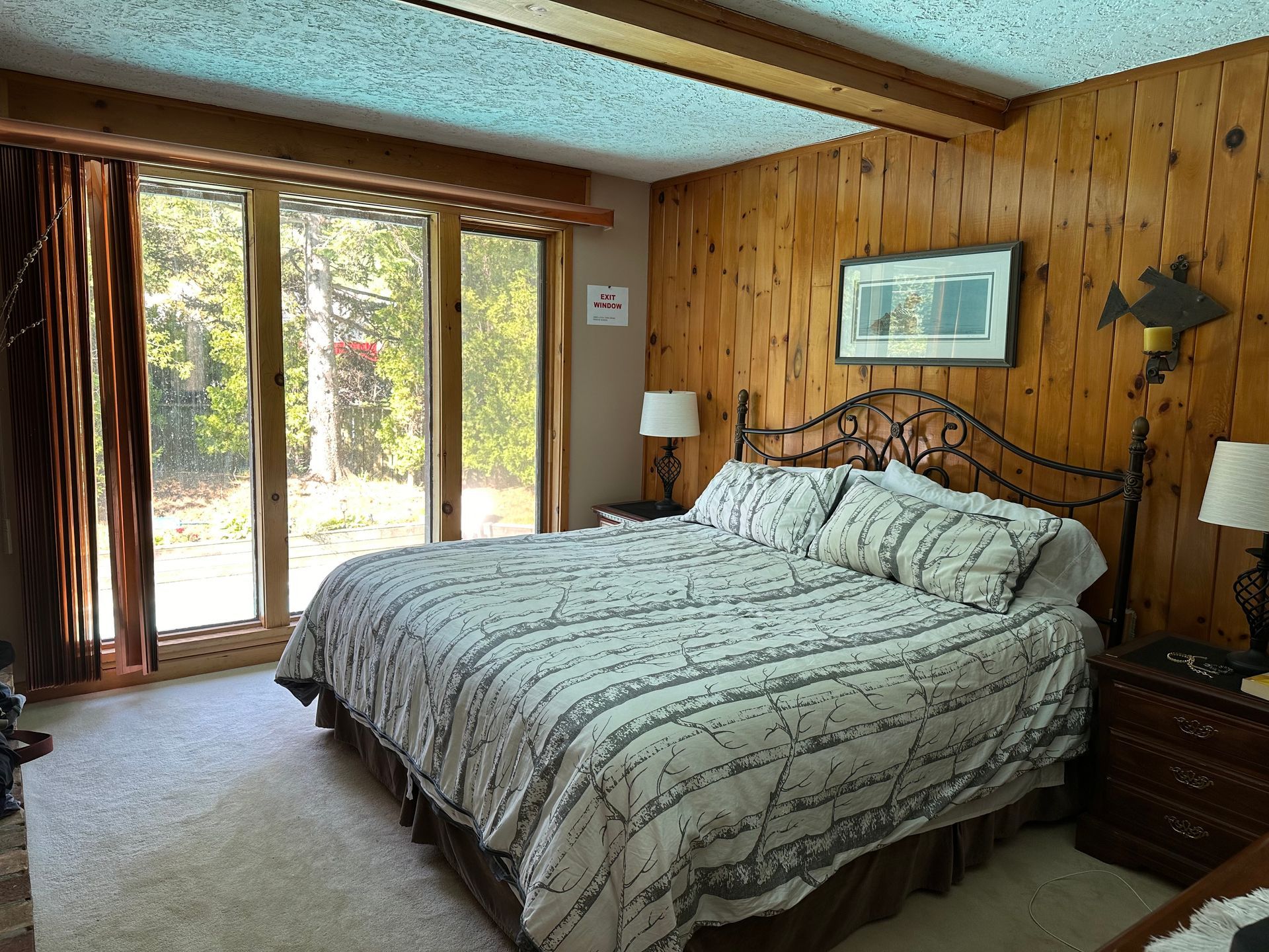 A bedroom with a king size bed and a large window.