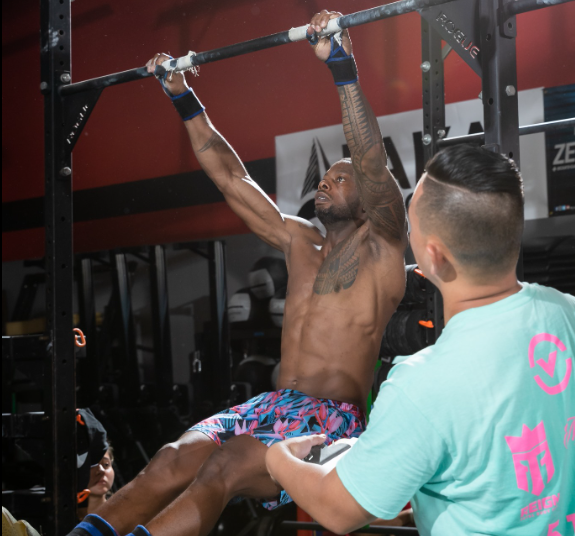 A man is doing a pull up while another man watches
