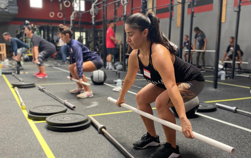 A woman is squatting down with a barbell in a gym.
