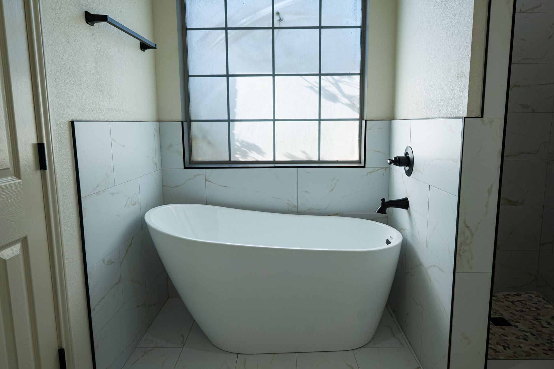A white bathtub is sitting in a bathroom next to a window.