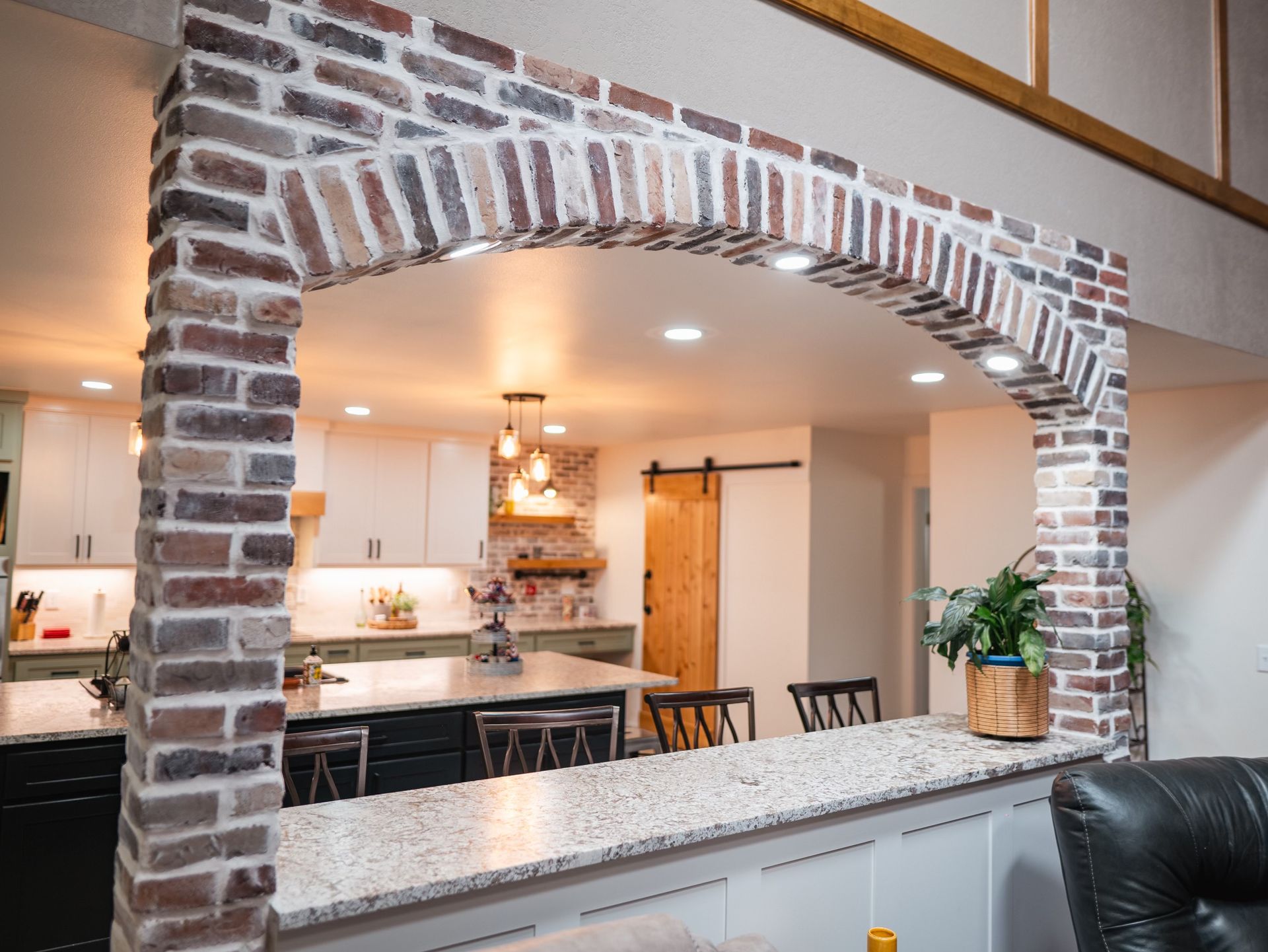 A kitchen with a brick archway between the kitchen and the living room.