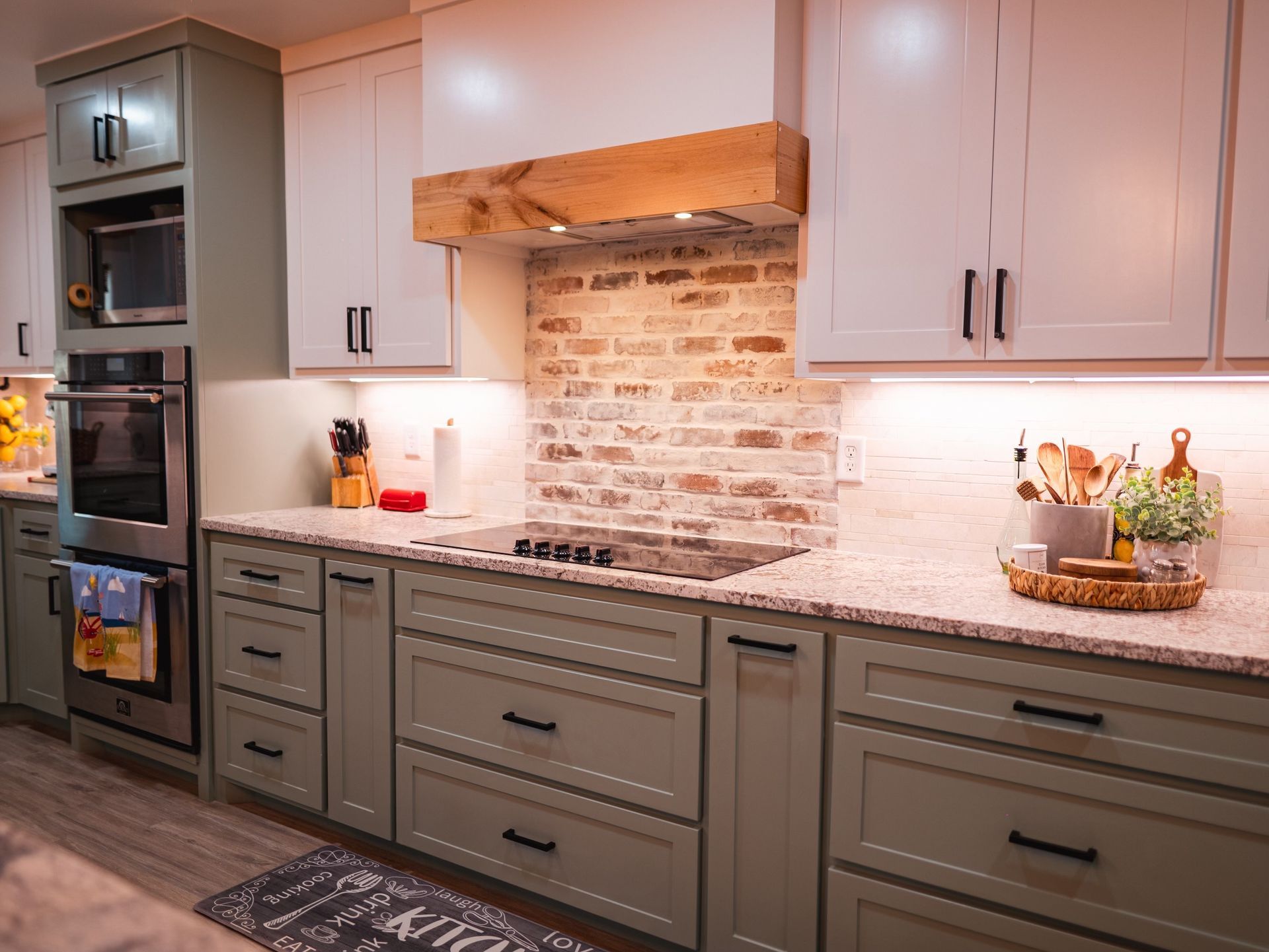 A kitchen with green cabinets , white cabinets , granite counter tops and a stove.