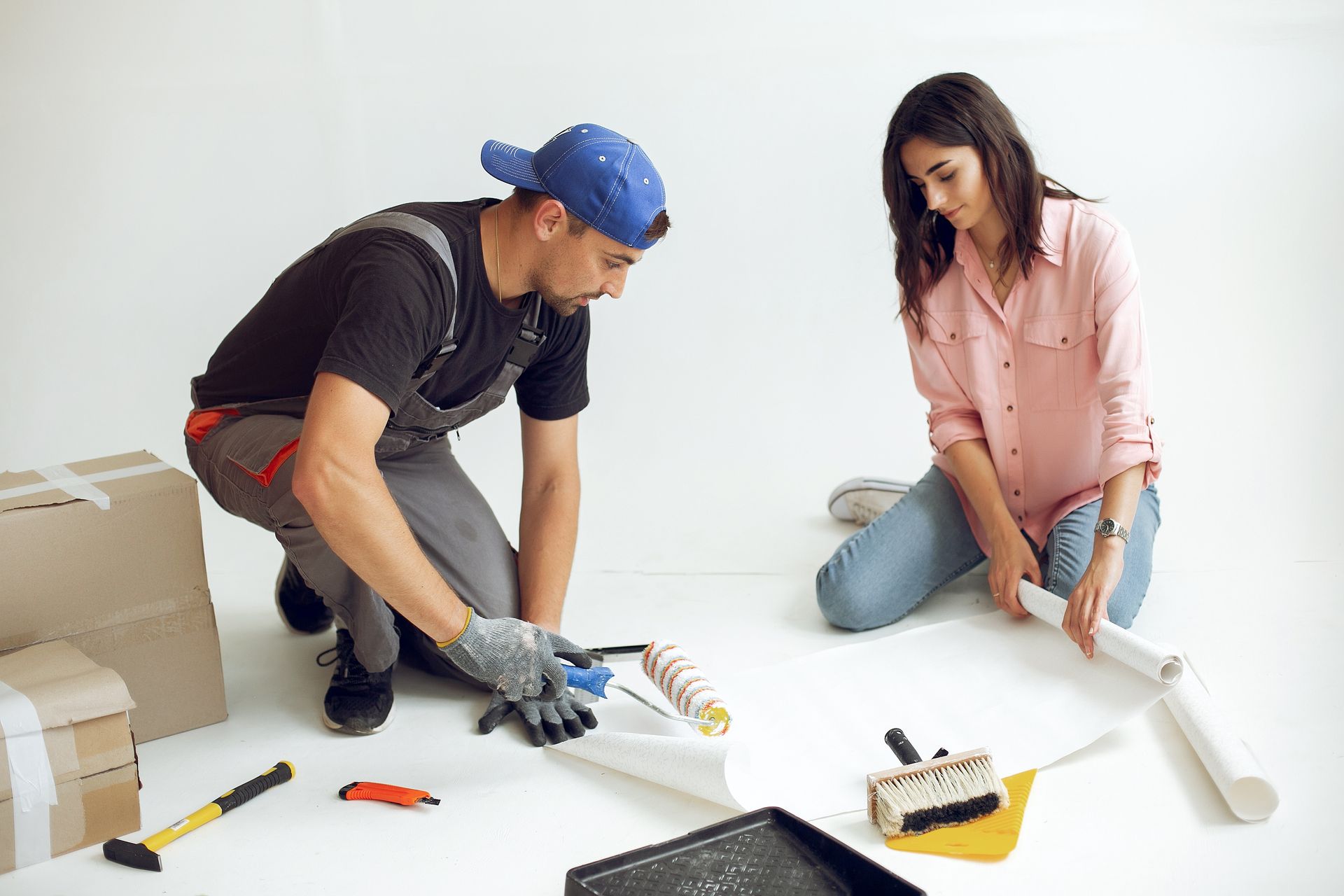 Couple preparing wallpaper and tools for a home renovation project.