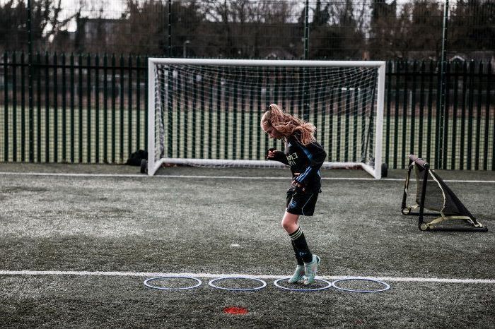 A young girl is kicking a soccer ball on a field.