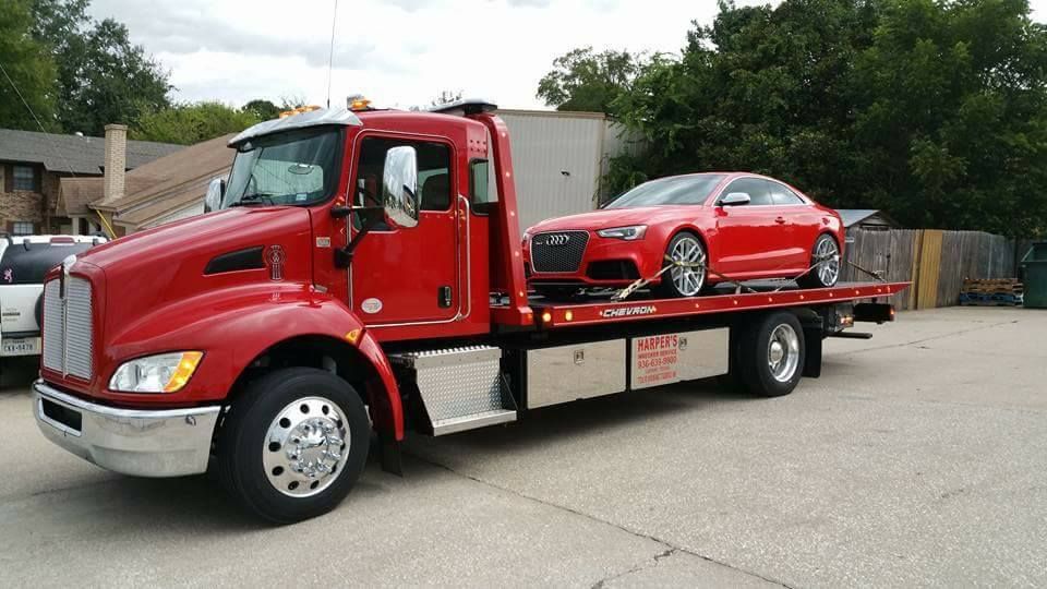 A red tow truck is carrying two red cars.