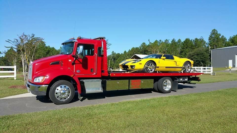 A red tow truck is carrying a yellow sports car.