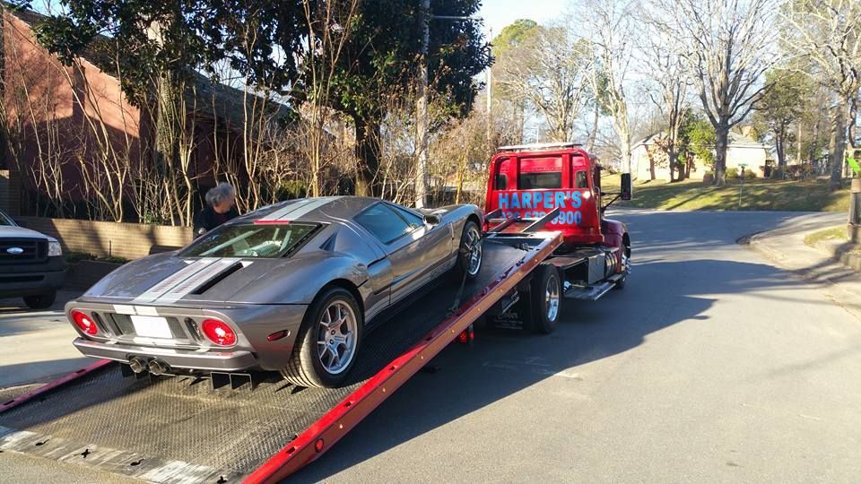 A silver sports car is being towed by a tow truck