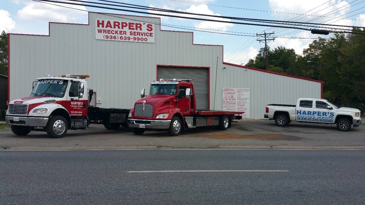 Three tow trucks are parked in front of a building.