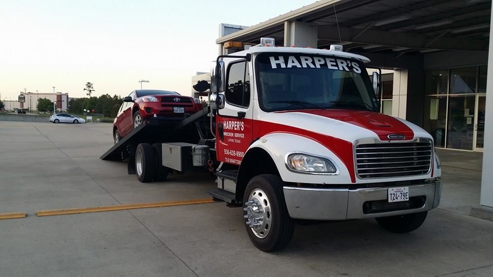 A harper 's tow truck is towing a red car