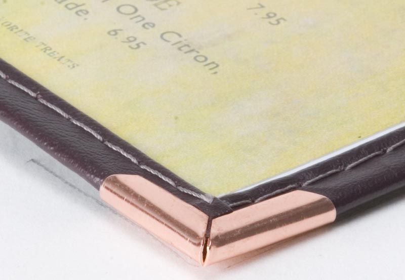 a close up of a menu with a copper corner