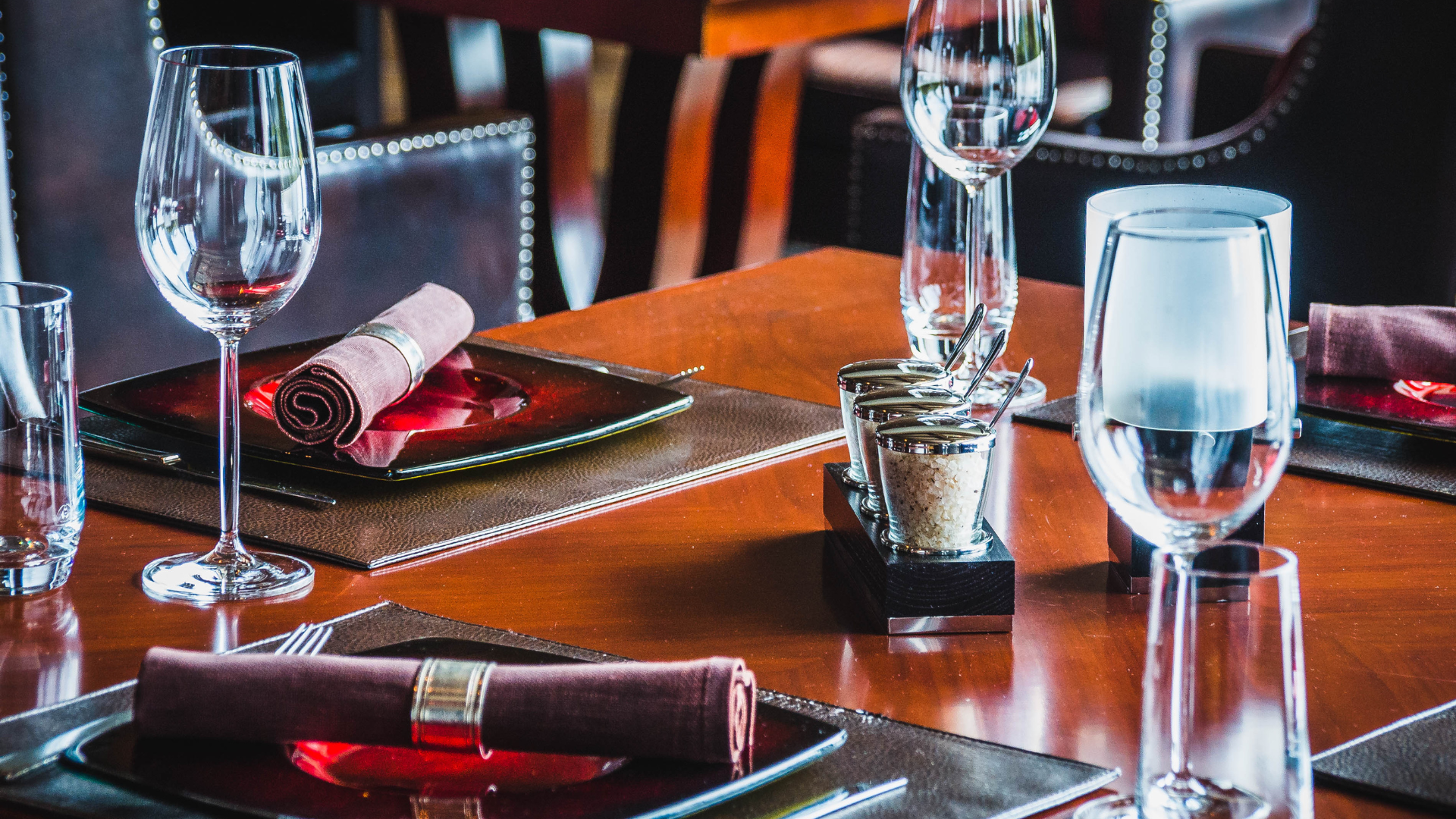 a wooden table with plates , wine glasses , and candles on it with placemat