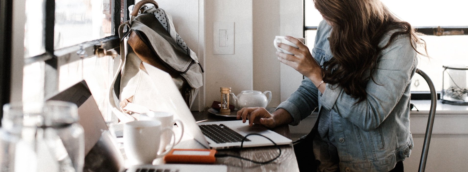 une femme est assise à une table avec un ordinateur portable et une tasse de café .