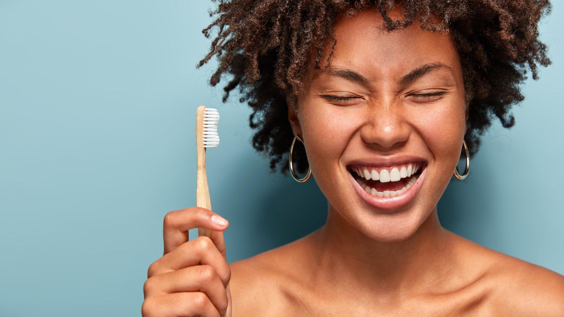 A woman is holding a toothbrush in her hand and smiling.