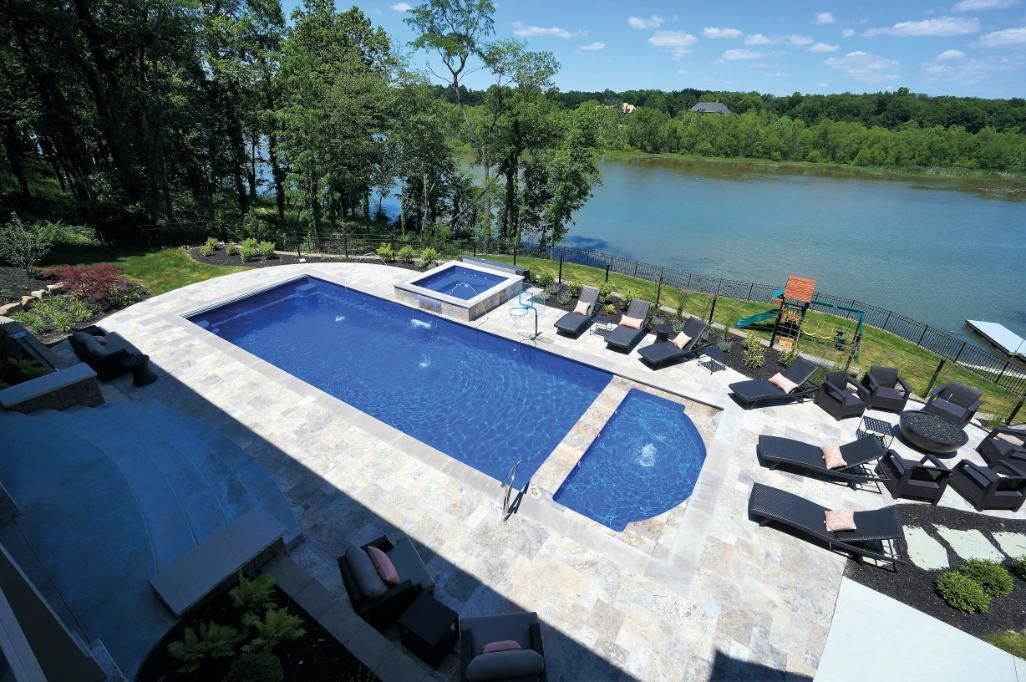 An aerial view of a large swimming pool with a lake in the background.