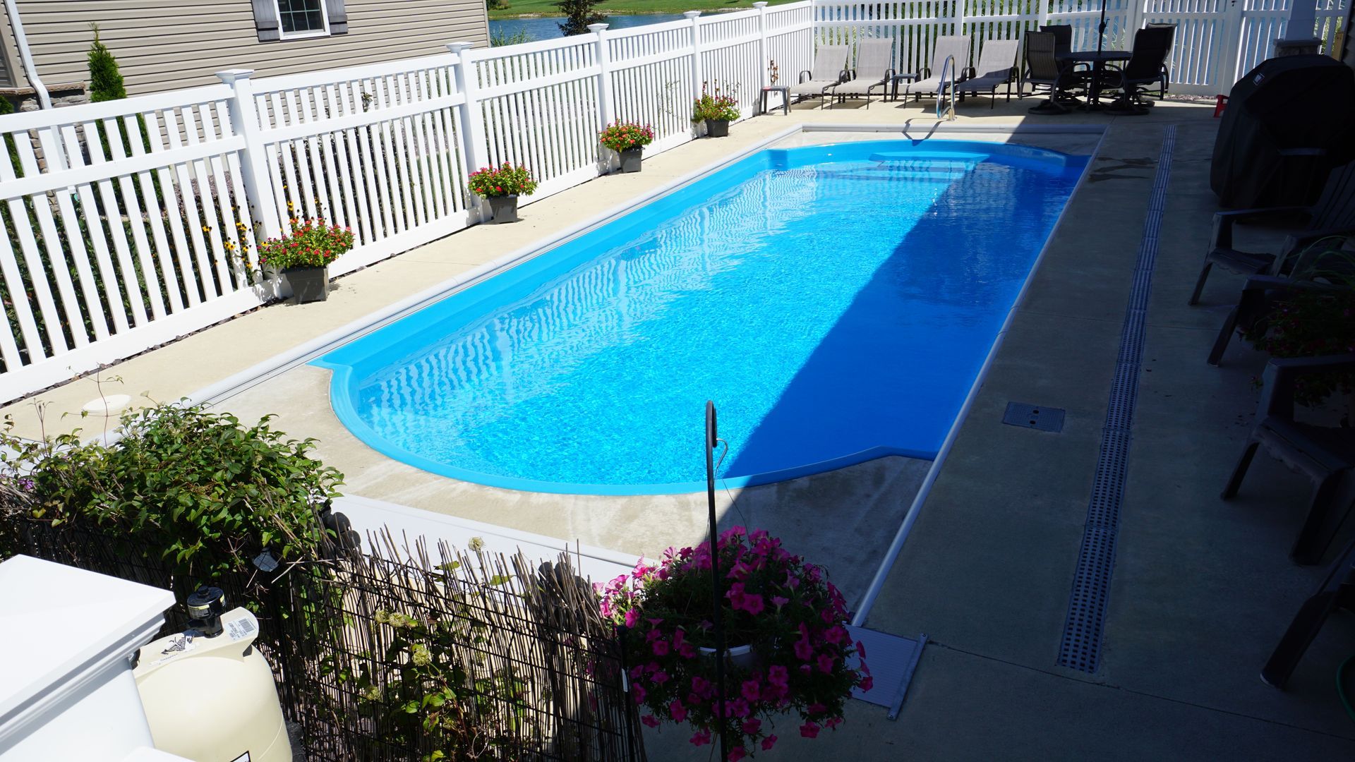 A large swimming pool with a white fence surrounding it.