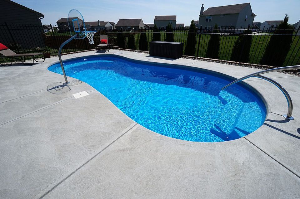 A large blue swimming pool with a basketball hoop in the backyard.