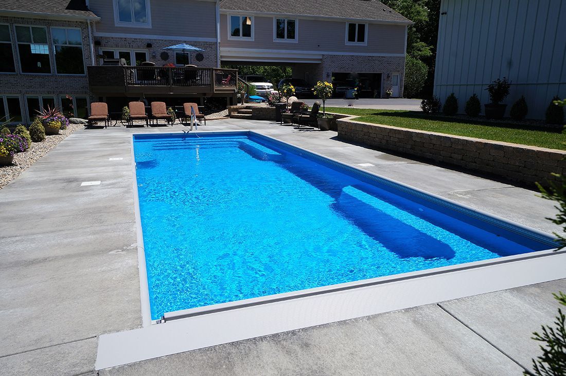 Blue rectangular pool with steps in a backyard setting.