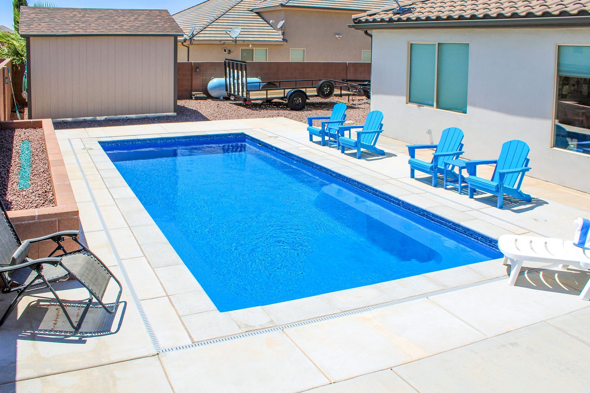 A large swimming pool with blue chairs around it
