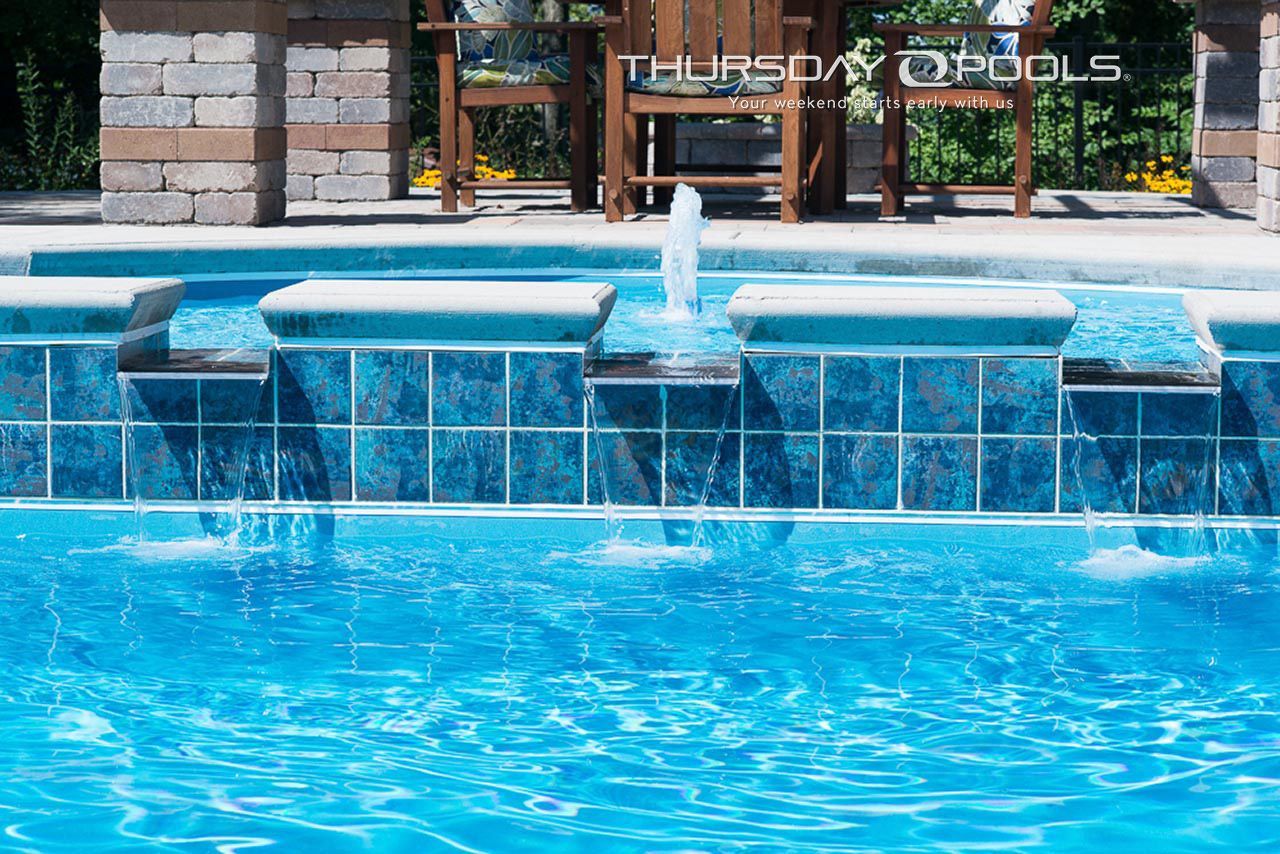 A swimming pool with a fountain in the middle of it