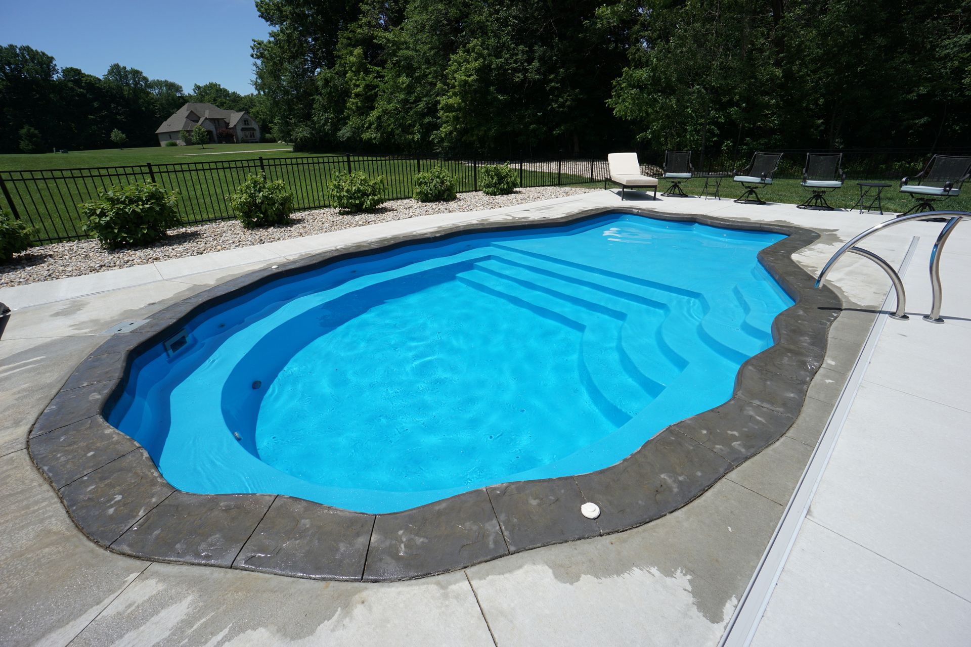 A large oval shaped swimming pool with blue water