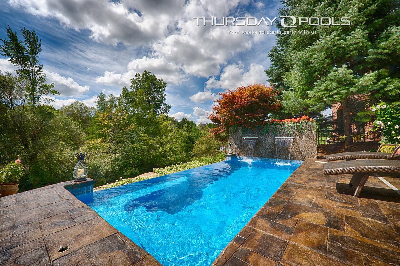 A large swimming pool with a waterfall in the backyard on thursday pools