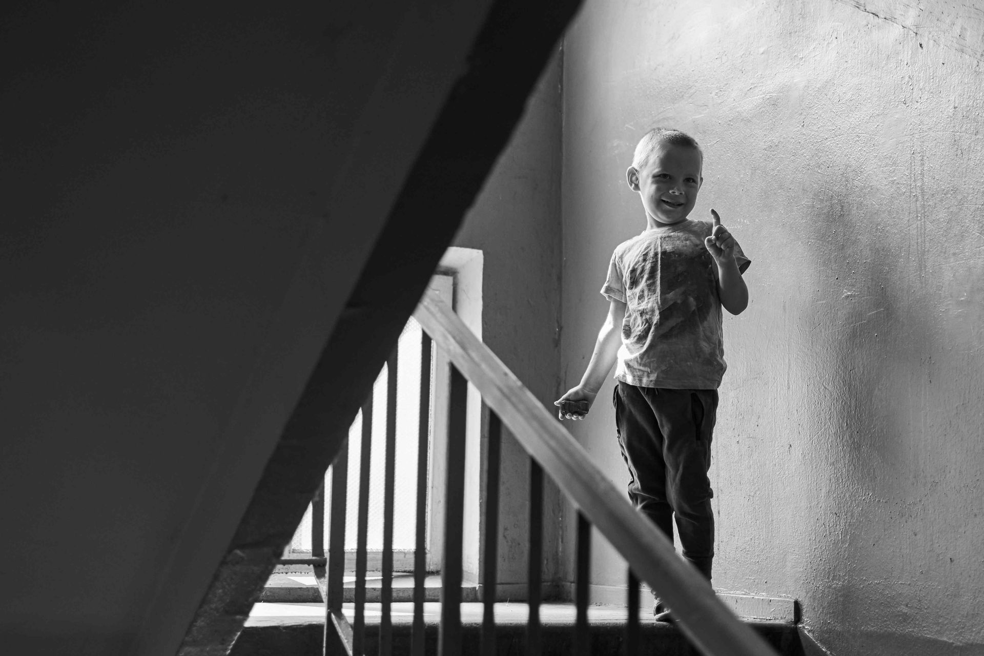 A lifestyle photograph of a boy standing on the steps by the railing on the landing