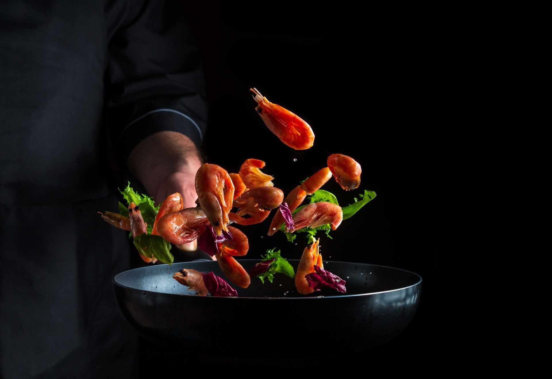 A professional photograph of a man making a shrimp stir fry meal in a pan to promote his Texas business
