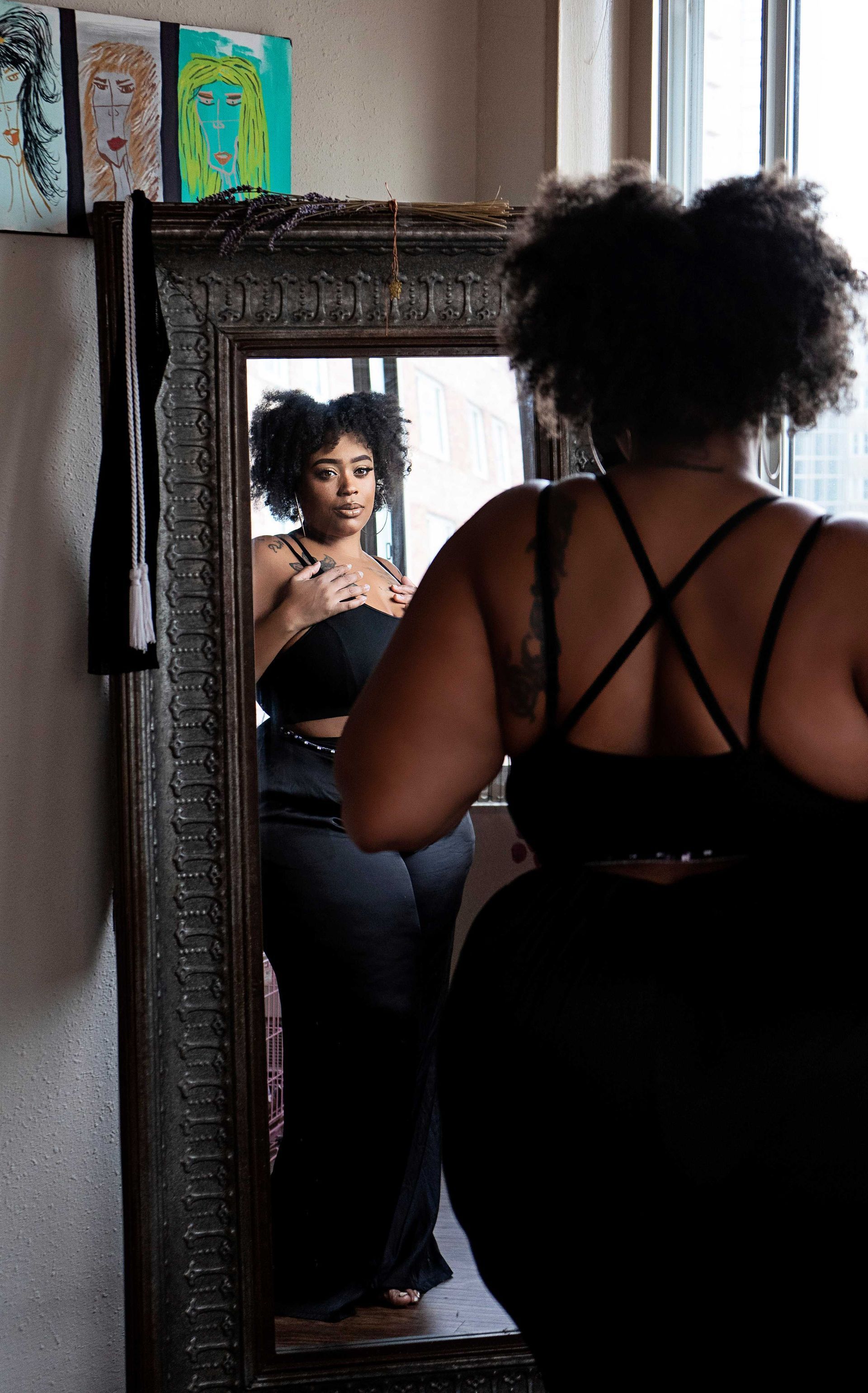 A plus-sized woman posing in the mirror during a photography session