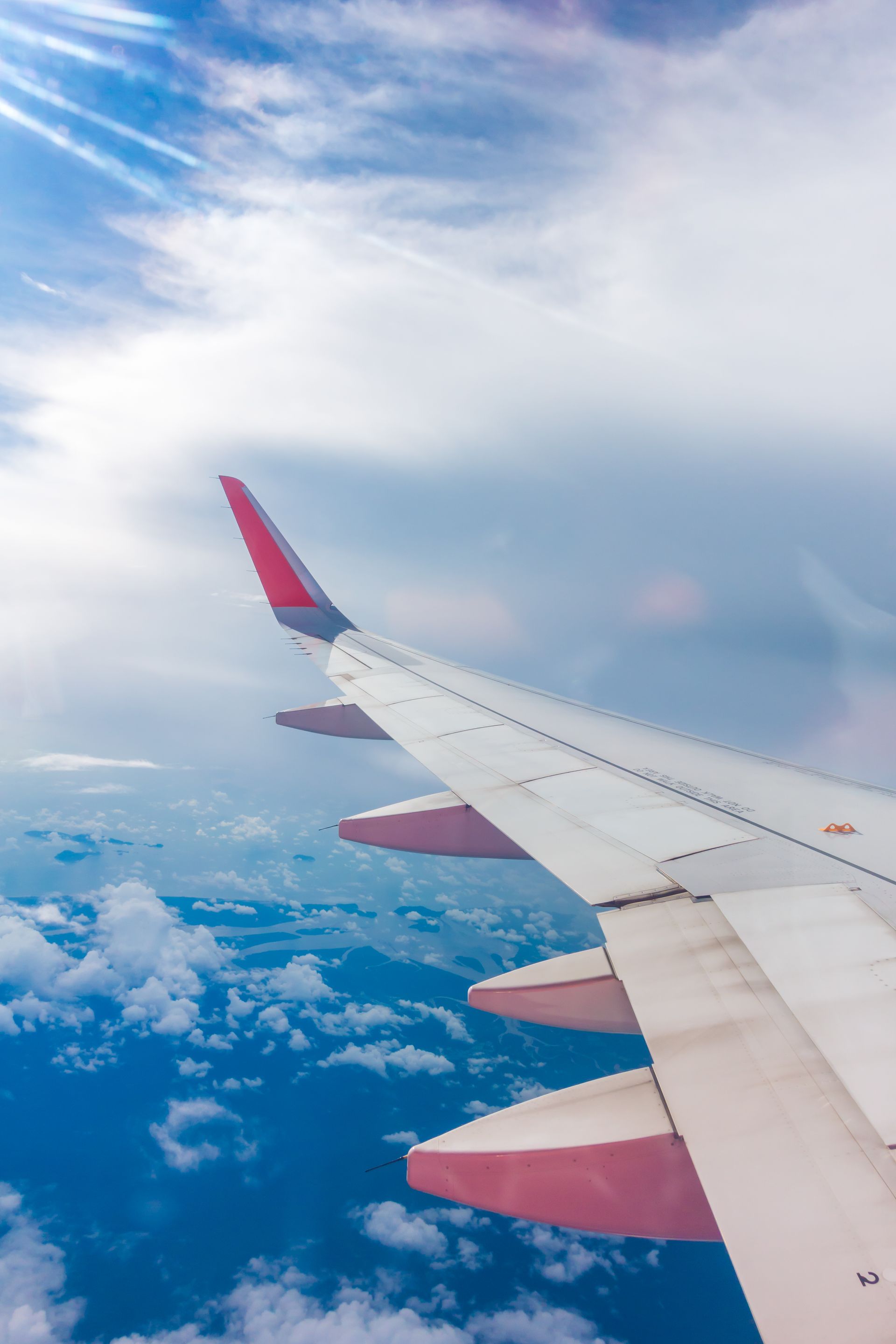 The wing of an airplane is flying in the sky.