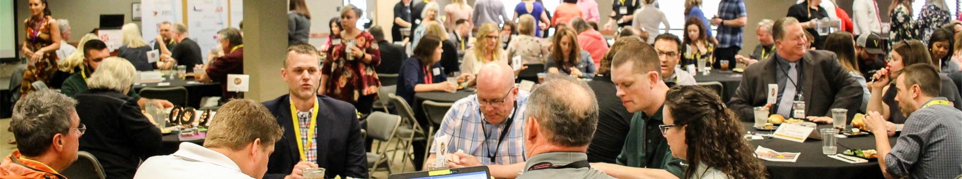 A large group of people are sitting at tables in a room.