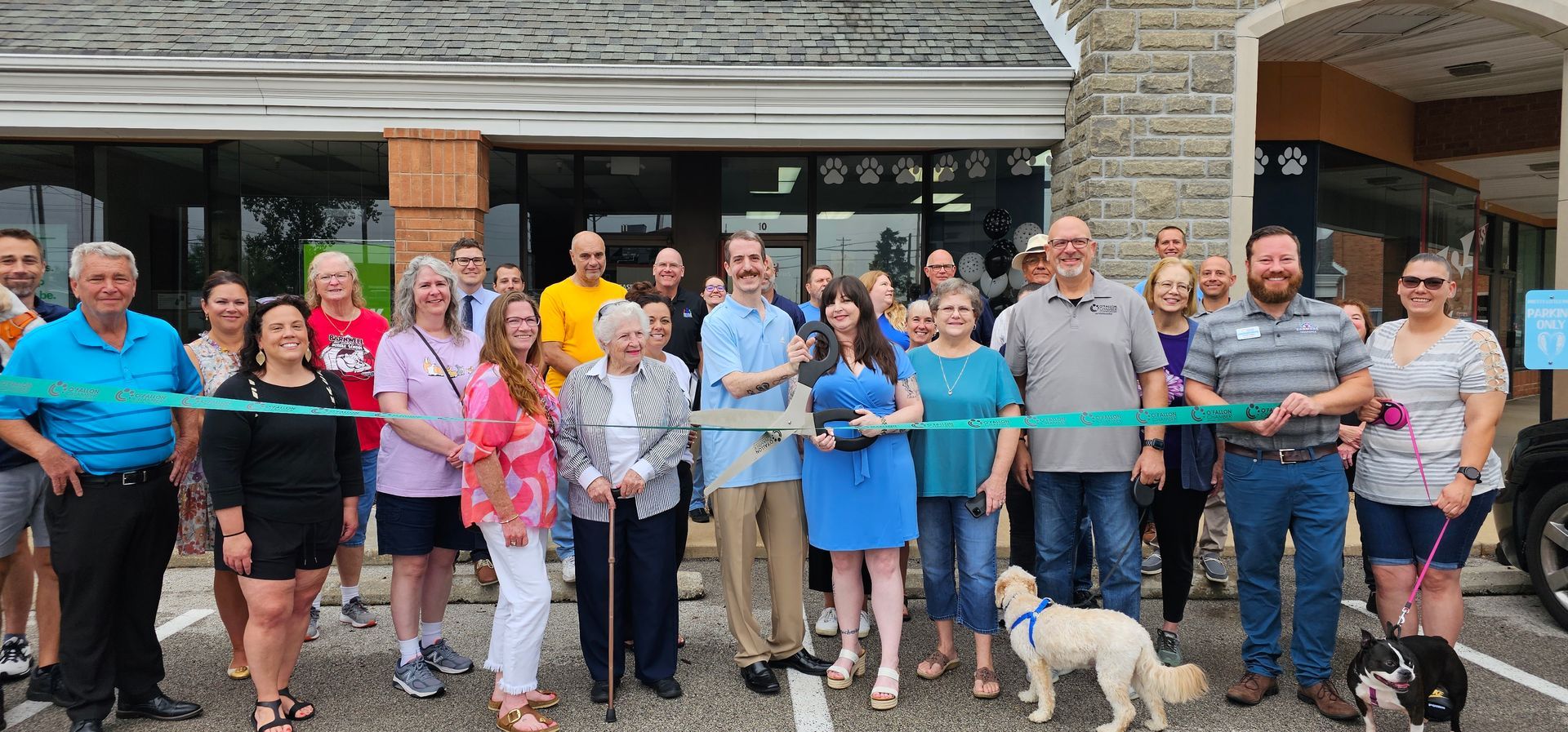 A group of people are standing in front of a building cutting a ribbon.