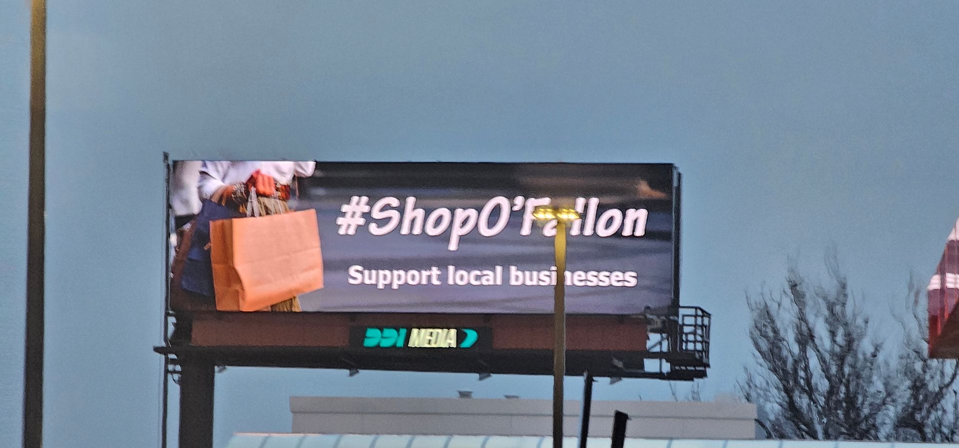 A billboard on the side of a highway that says #shopofashion