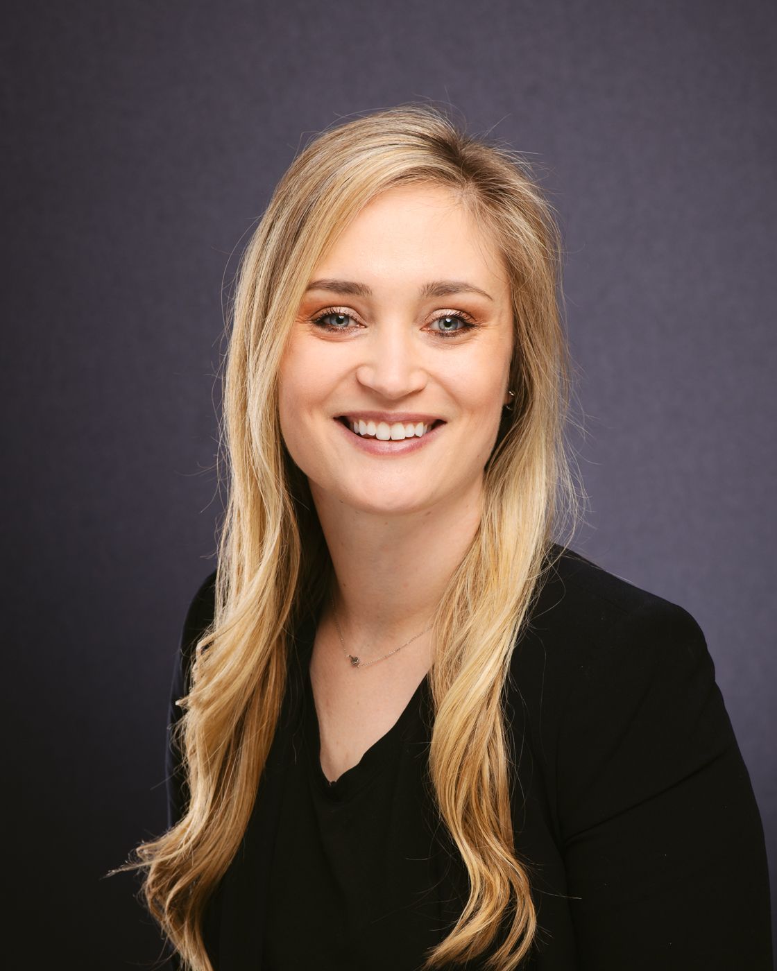 The woman is wearing a black jacket and smiling for the camera.