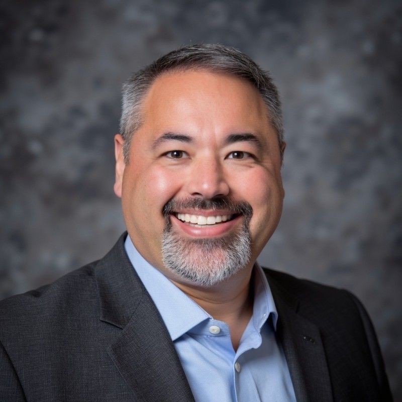 A man with a beard and tie is smiling for the camera.