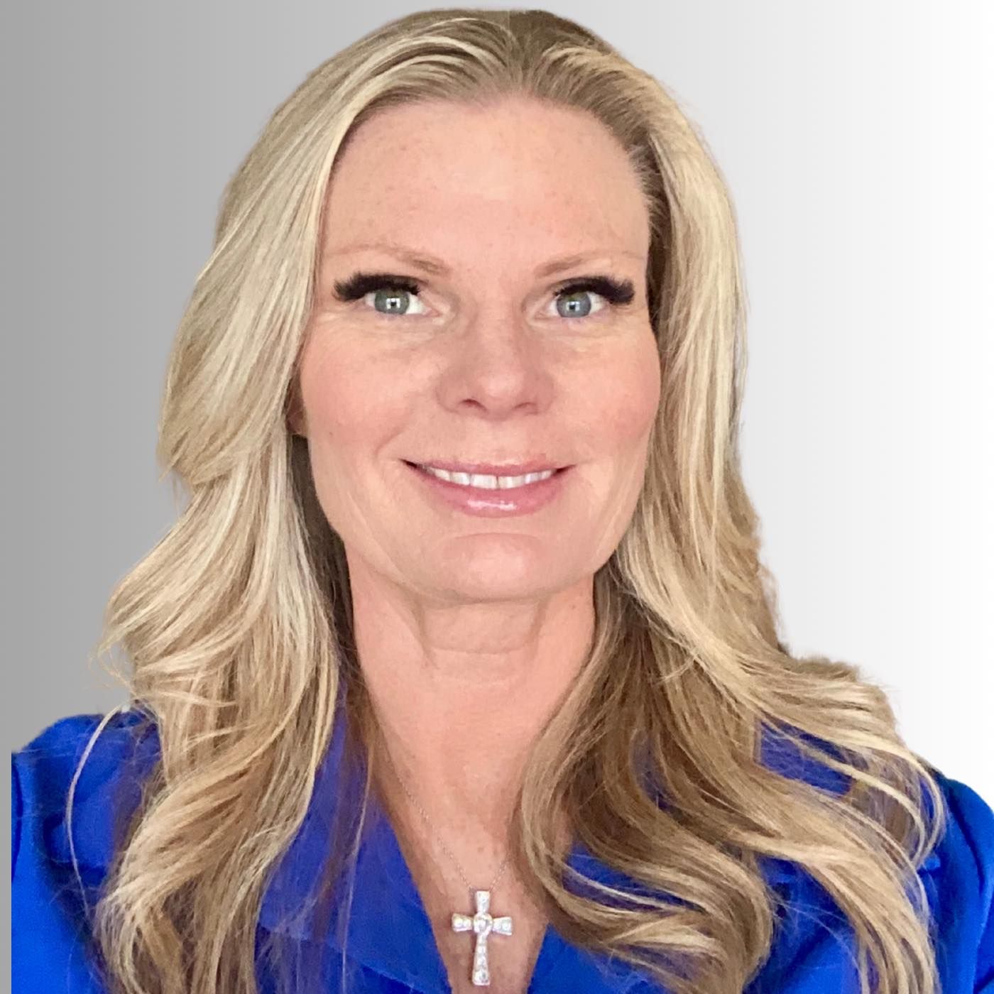 A woman in a green shirt is sitting in front of a painting.