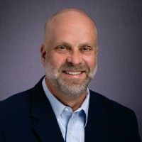 A bald man with a beard is wearing a suit and smiling for the camera.