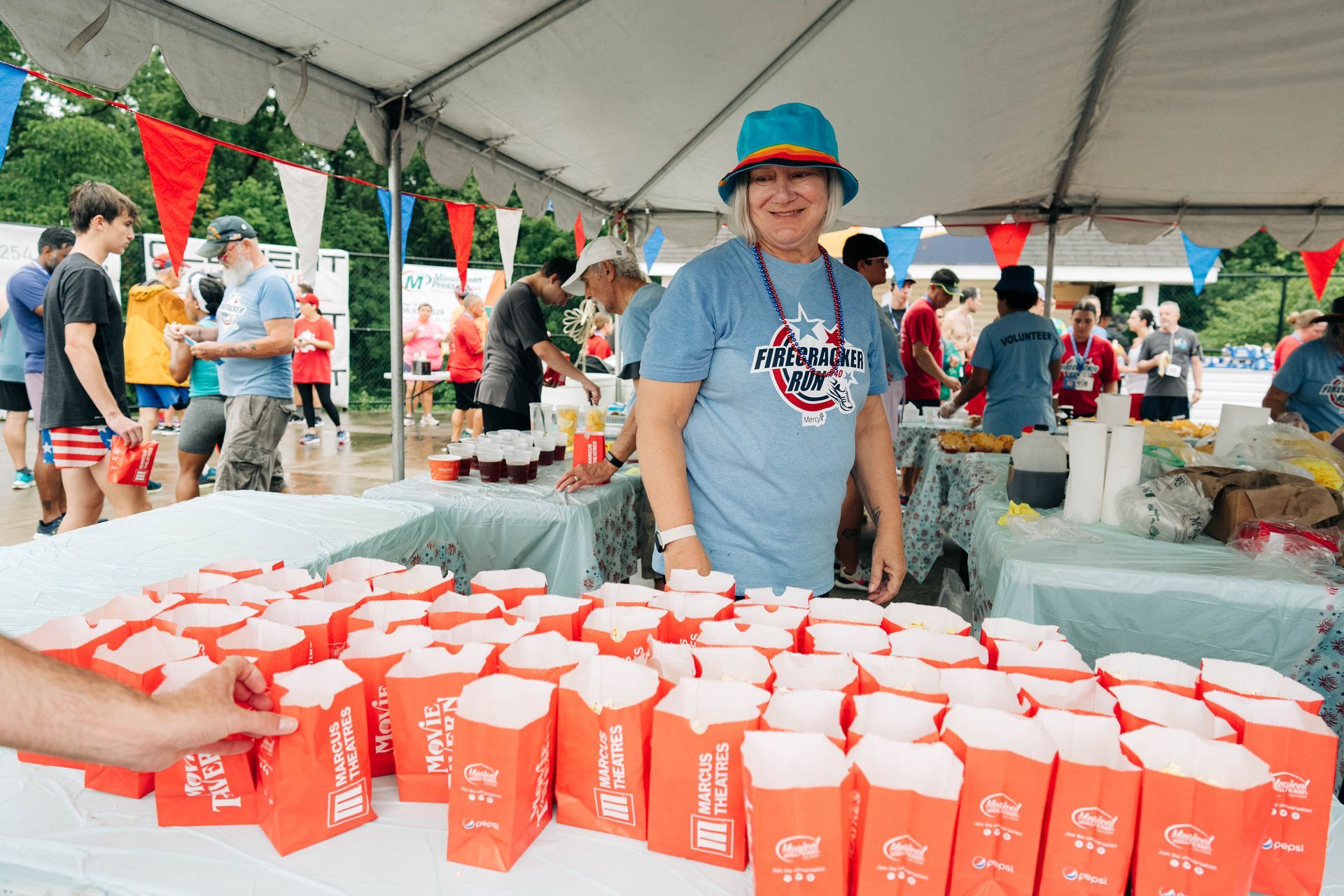 A woman is standing in front of a table full of popcorn boxes.