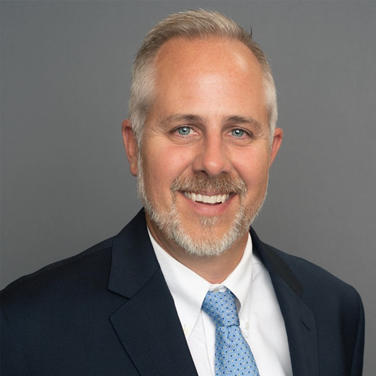 A man in a suit and tie is smiling for the camera.