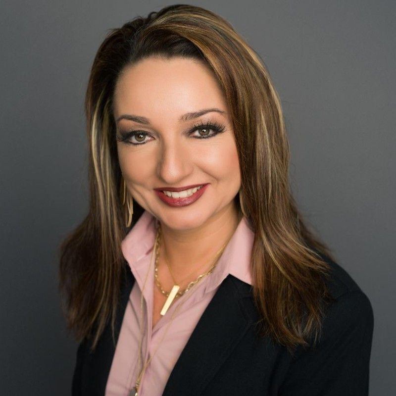 A woman is smiling in front of a palm tree.