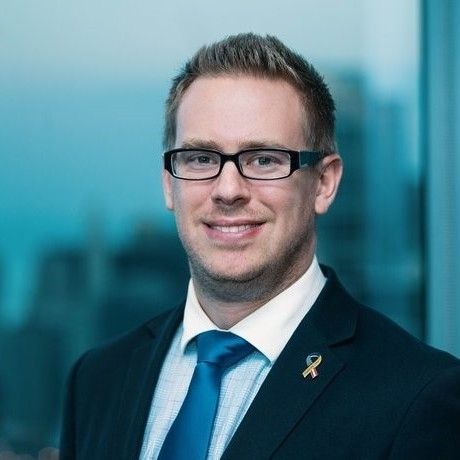A woman in a blue shirt and necklace is smiling for the camera.