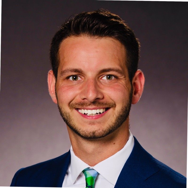 A man in a suit and tie is smiling for the camera.