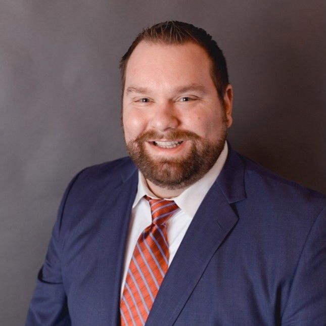 A man with a beard and tie is smiling for the camera.