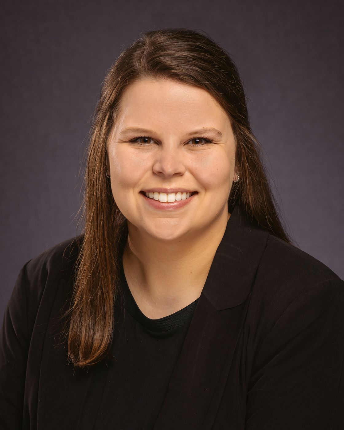 A woman in a black jacket is smiling for the camera.