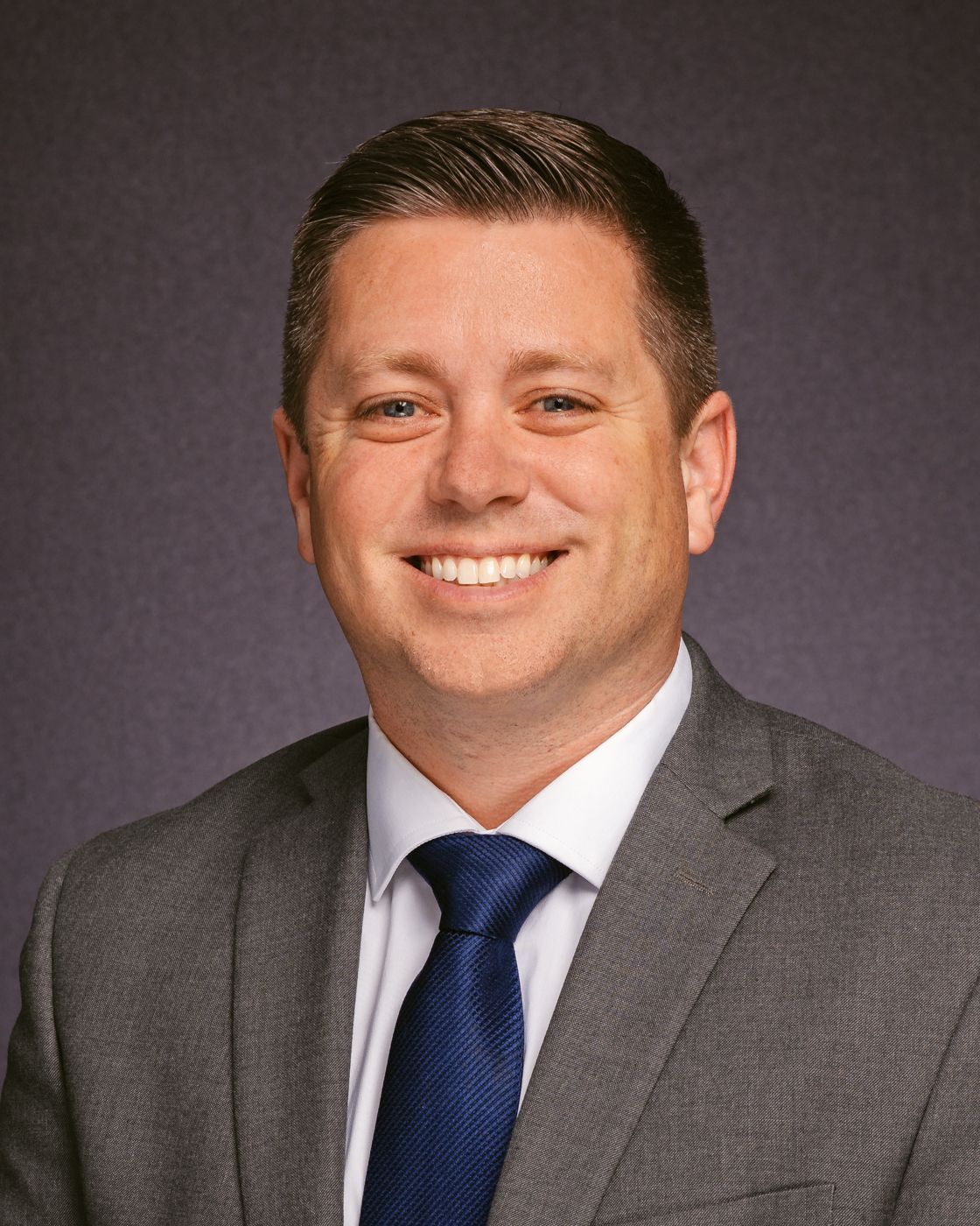 A man in a suit and tie is smiling for the camera.