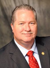 A man in a suit and tie is smiling for the camera.