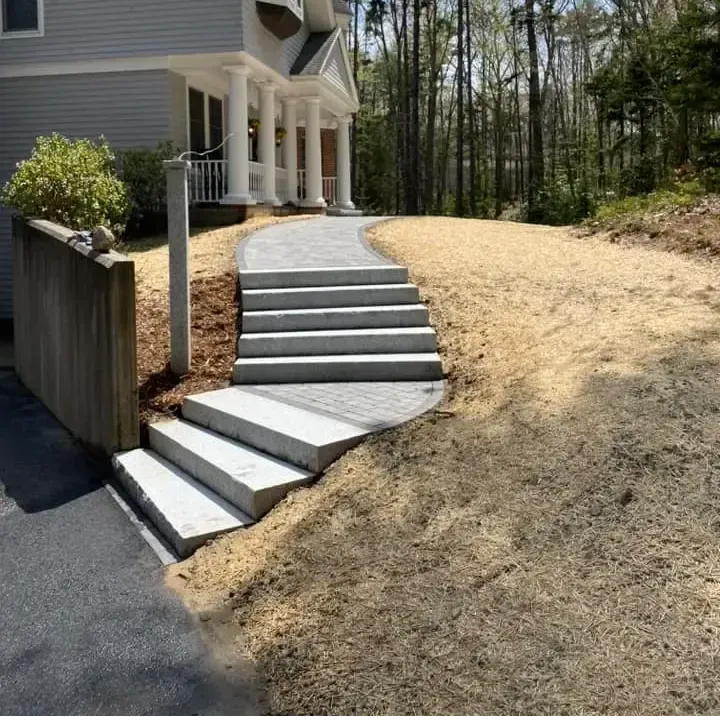 A concrete walkway with stairs leading up to a house