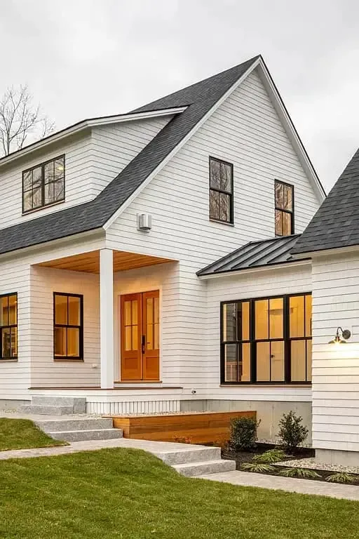 A large white house with a black roof and a porch.